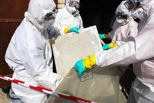 four people in hazmat suits cleaning up asbesto