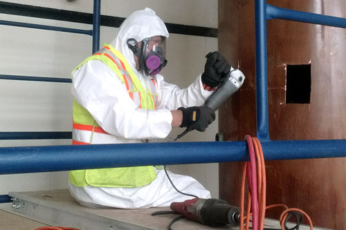 man in hazmat suit cutting copper